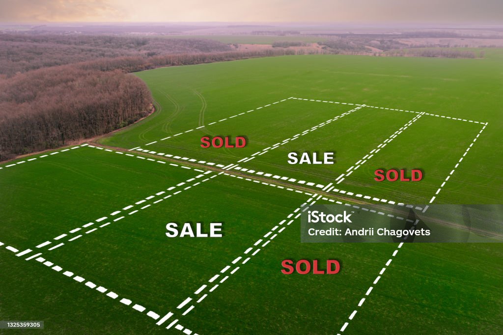 Marking of farm field plots with inscriptions Sold and Sold. Buying and selling Concept on the land market. A section of the field for Sale marked by a dotted line. Land with the harvest for sale.